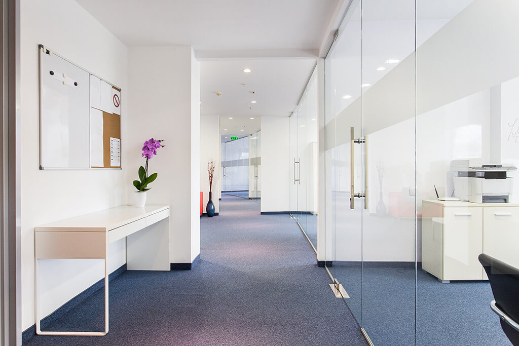 Good looking white office space with glass doors and bluish gary carpets