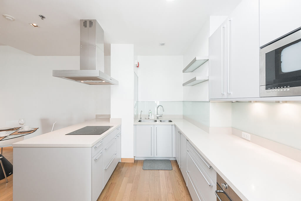 Clean white kitchen with white oak wood floor and stainless electros